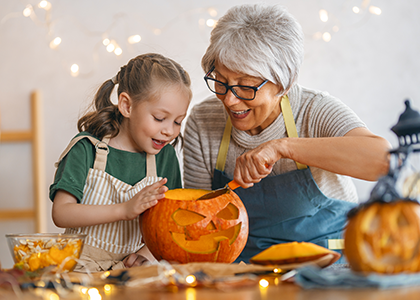 Grandmother carving pumpkin with her granddaughter