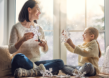 Mother and daughter cutting paper snowflakes