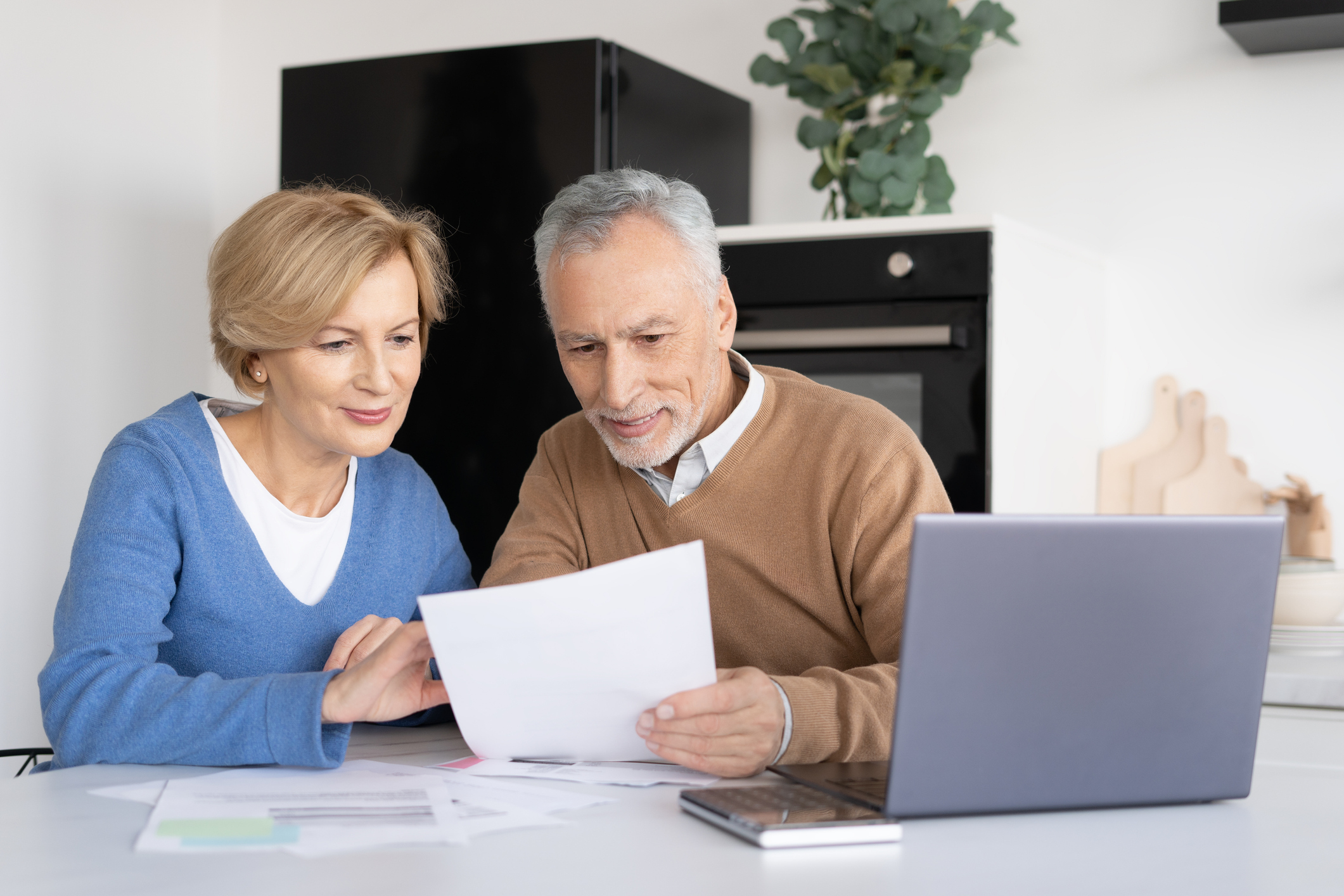 Portrait of middle-aged couple checking utility bills document. Planning family budget together. Process of calculating expenses. Counting taxes